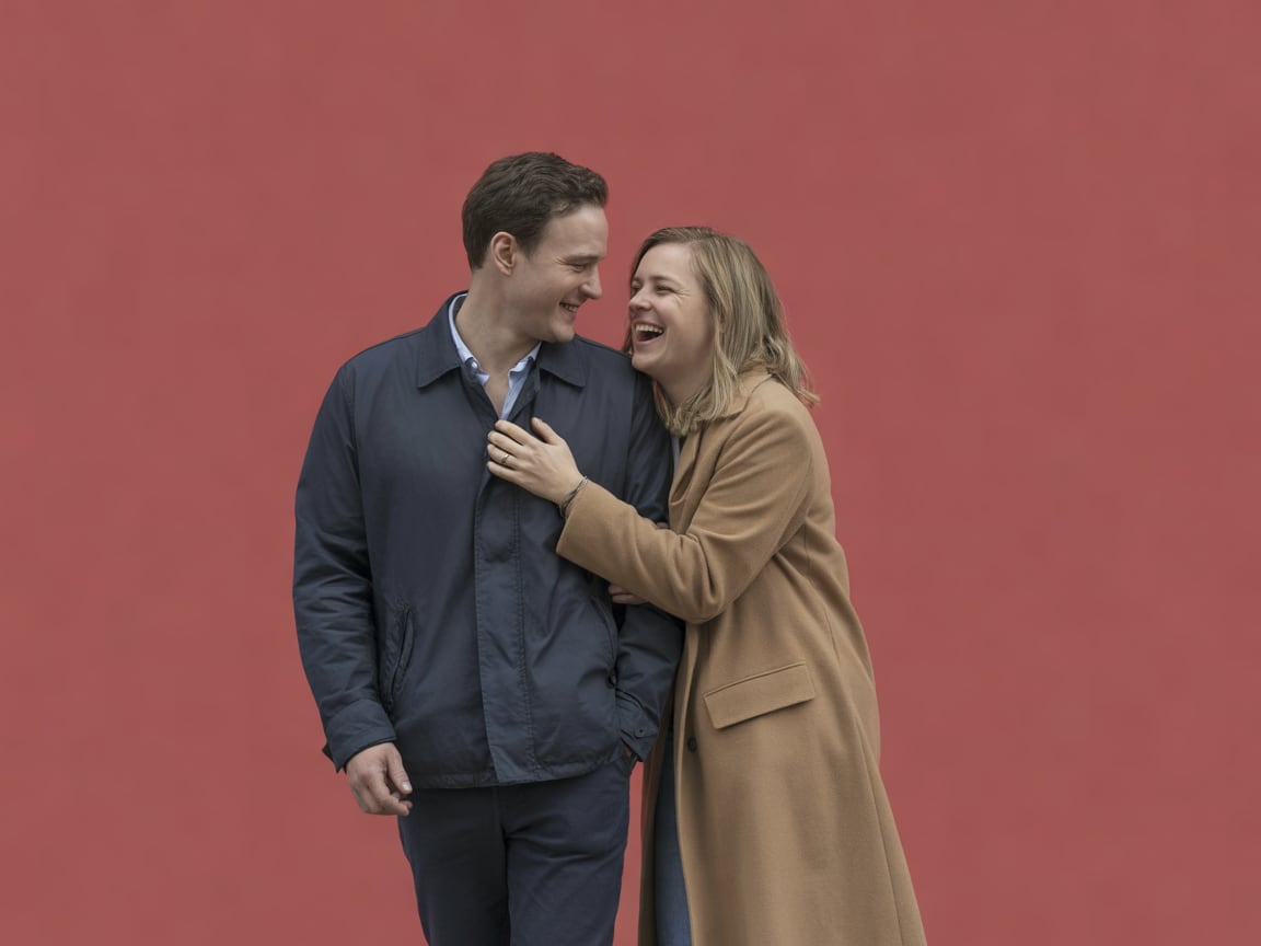 Candid photo of an ordinary couple in their thirties walking close together on a city street at early evening, he in a p